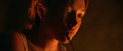 a woman in a dark room with a candle in her mouth