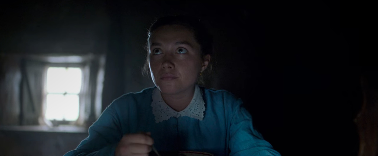 a woman sitting at a table in a dark room