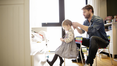 a man combing a little girl's hair in a bedroom