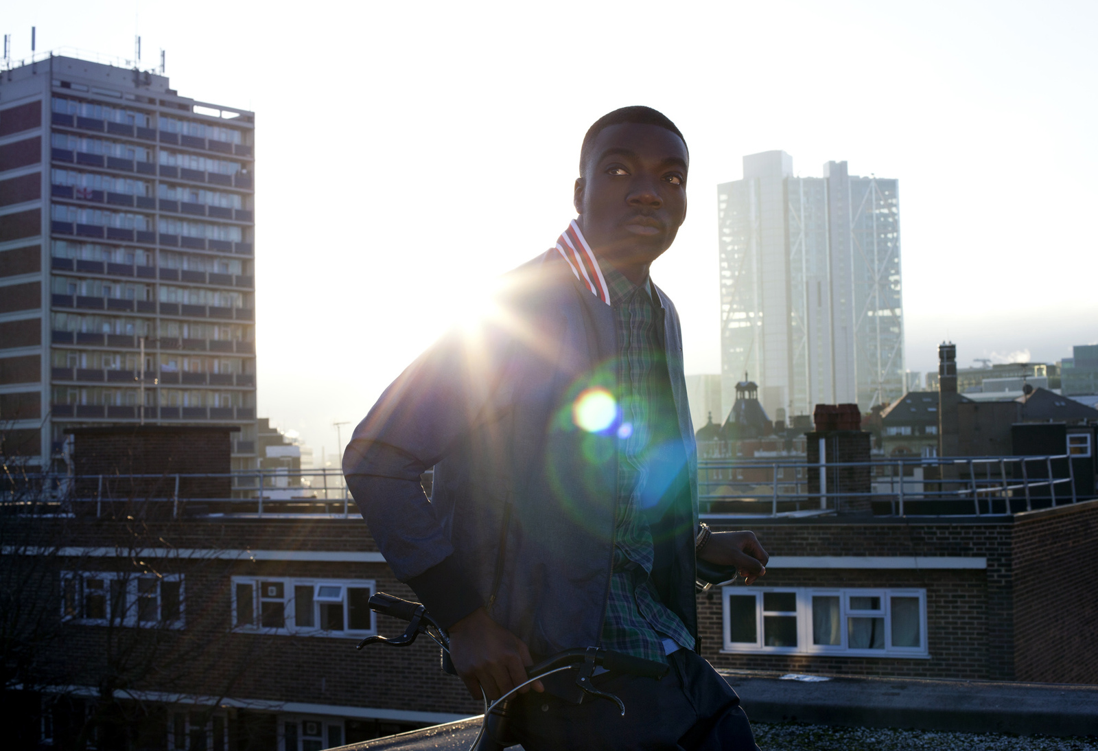 a man standing on top of a roof holding a skateboard