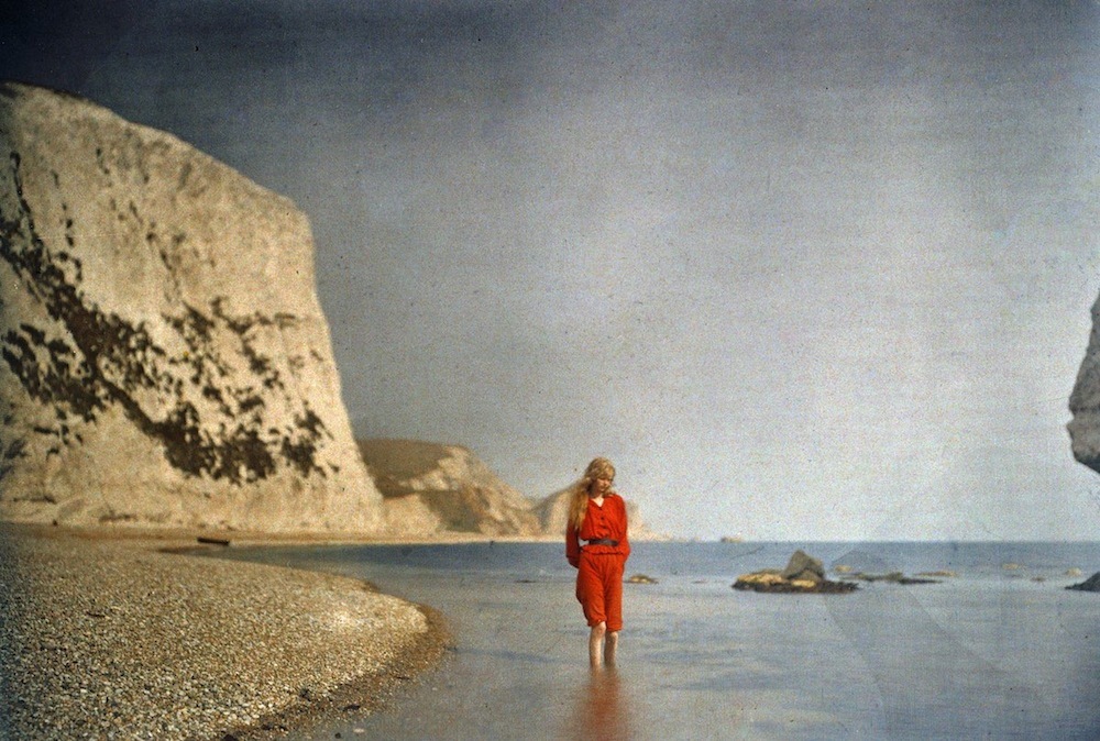 a woman in a red dress walking on the beach