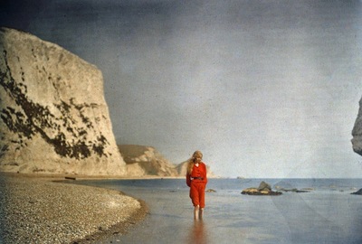 a woman in a red dress walking on the beach