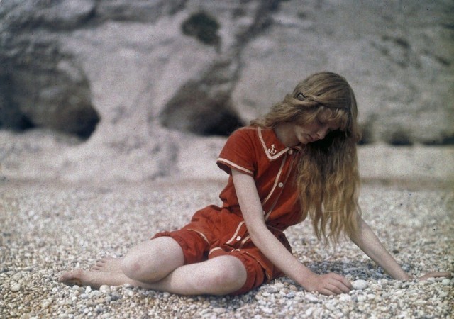 a young woman sitting on a rocky beach