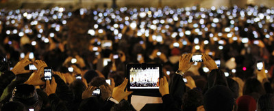 a crowd of people holding up their cell phones