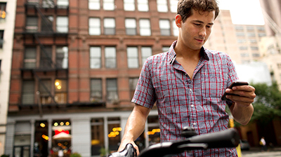 a man standing next to a bicycle looking at his cell phone