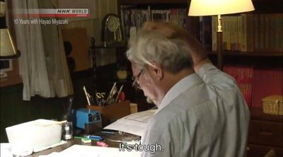 a man sitting at a desk in front of a book shelf