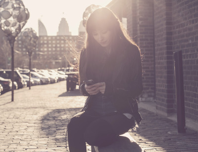 a woman sitting on a bench looking at her cell phone