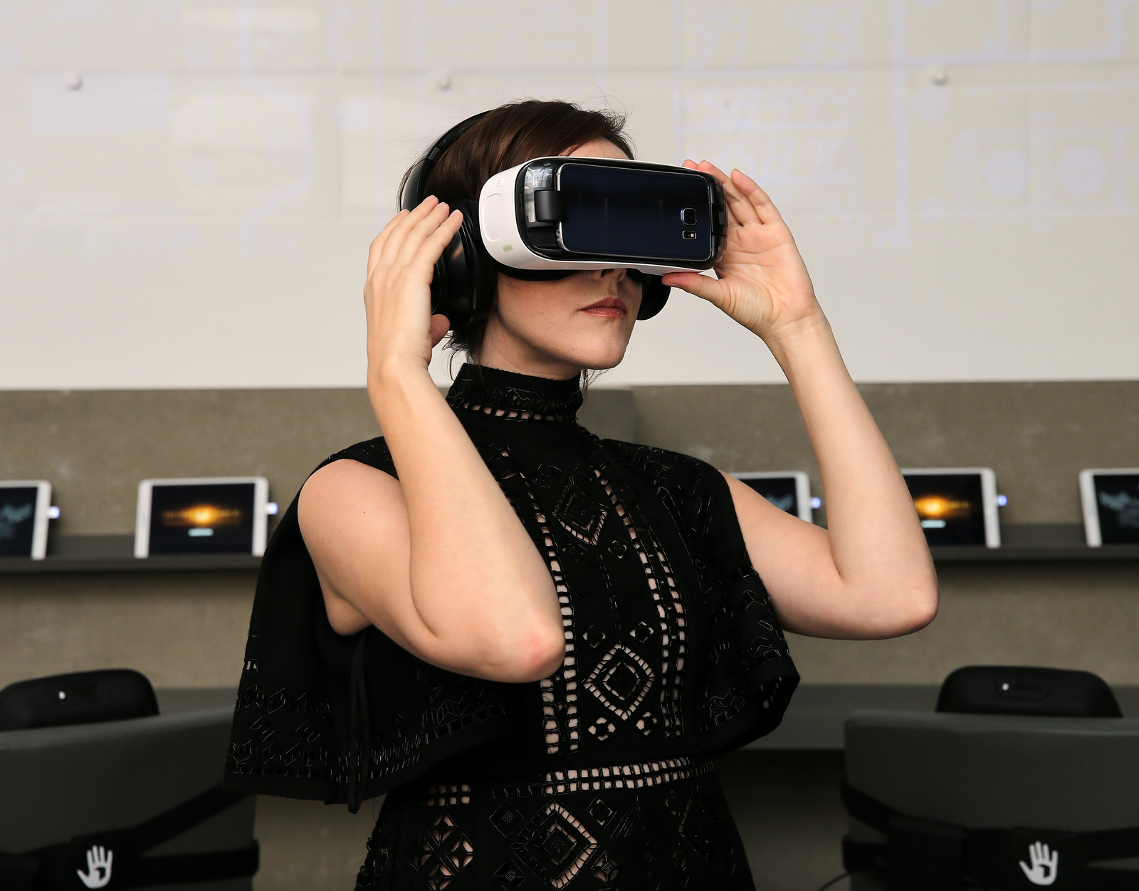 a woman in a black dress holding a cell phone up to her face