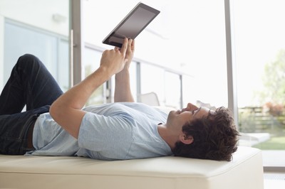 a man laying on a couch reading a book