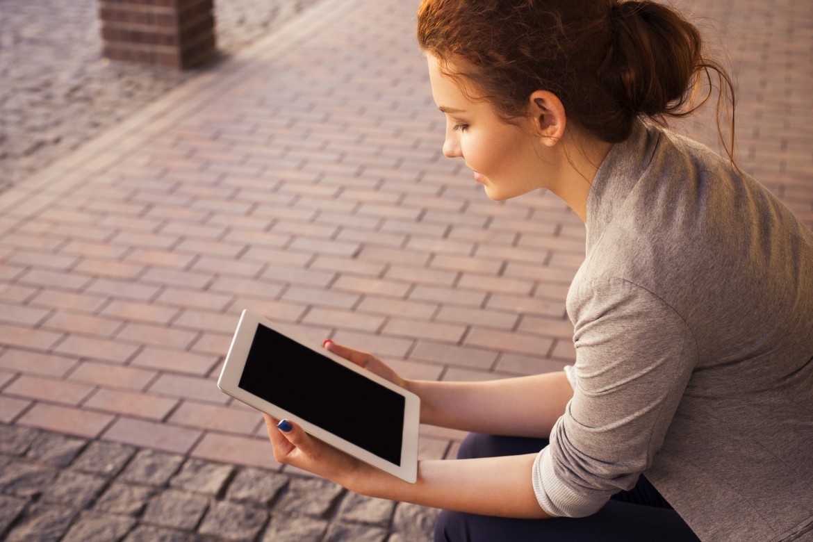 a woman sitting on the ground holding a tablet