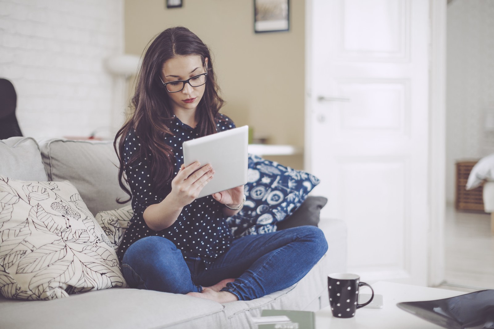 a woman sitting on a couch using a tablet