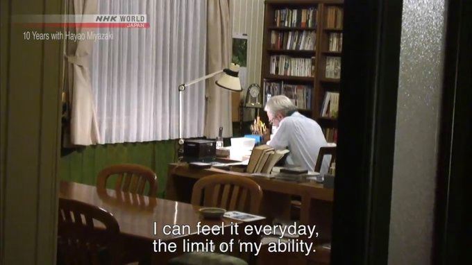 a man sitting at a desk in front of a book shelf