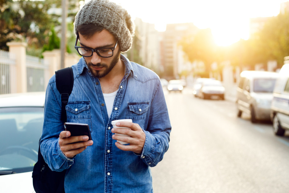 a man standing on a street looking at his cell phone