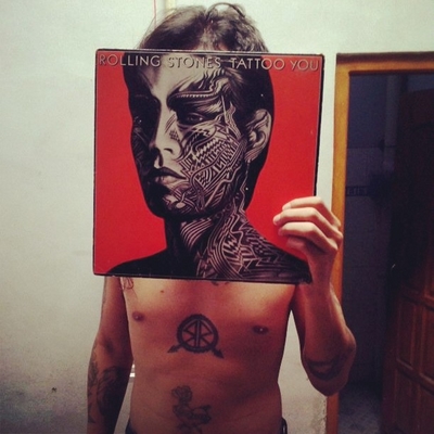 a man holding up a picture of a tattooed man