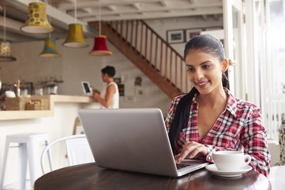 a woman sitting at a table using a laptop computer