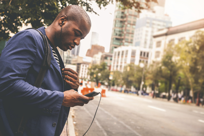 a man standing on the side of the road looking at his cell phone