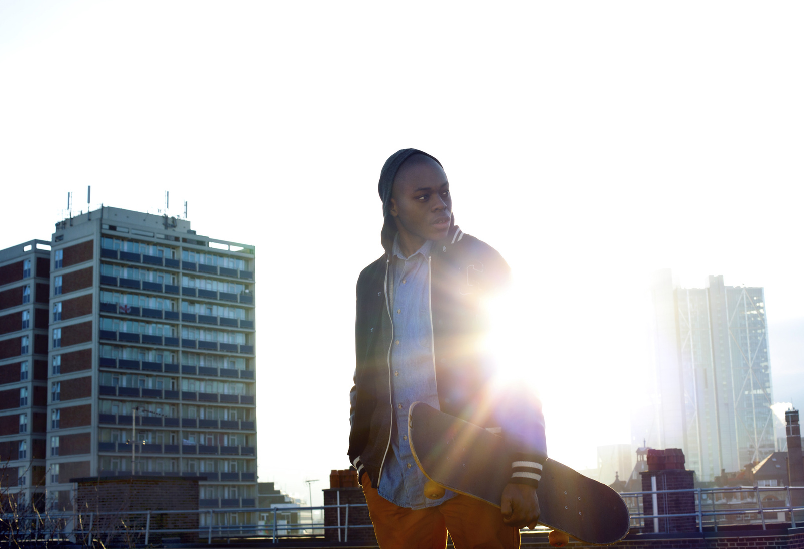 a woman holding a skateboard in front of a city skyline