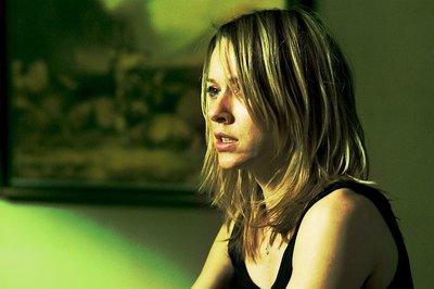 a woman sitting in front of a green wall