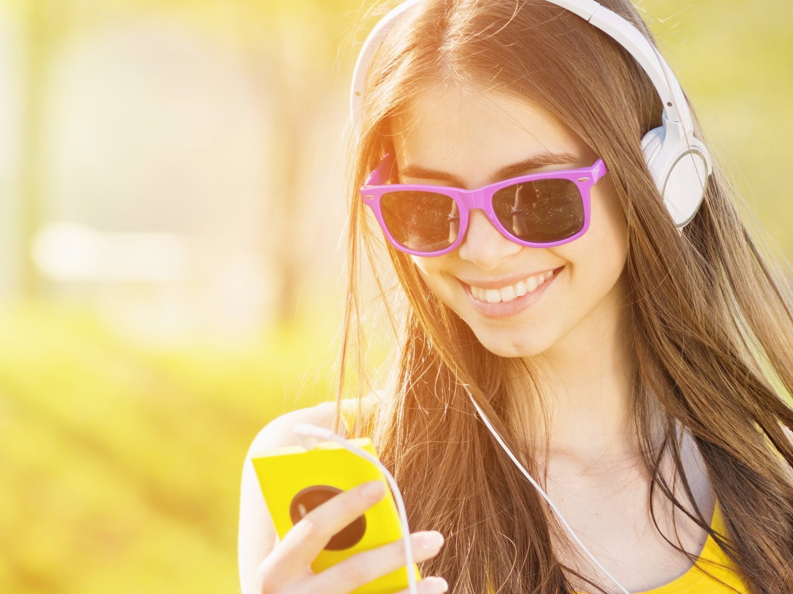 a young woman wearing headphones and holding a cell phone