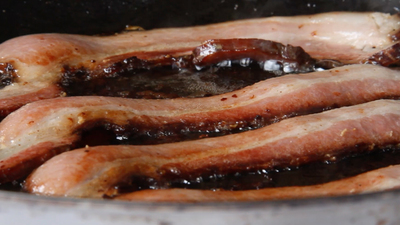 a close up of some bacon cooking in a pan