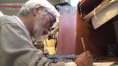 a man with a beard and glasses working on a piece of wood