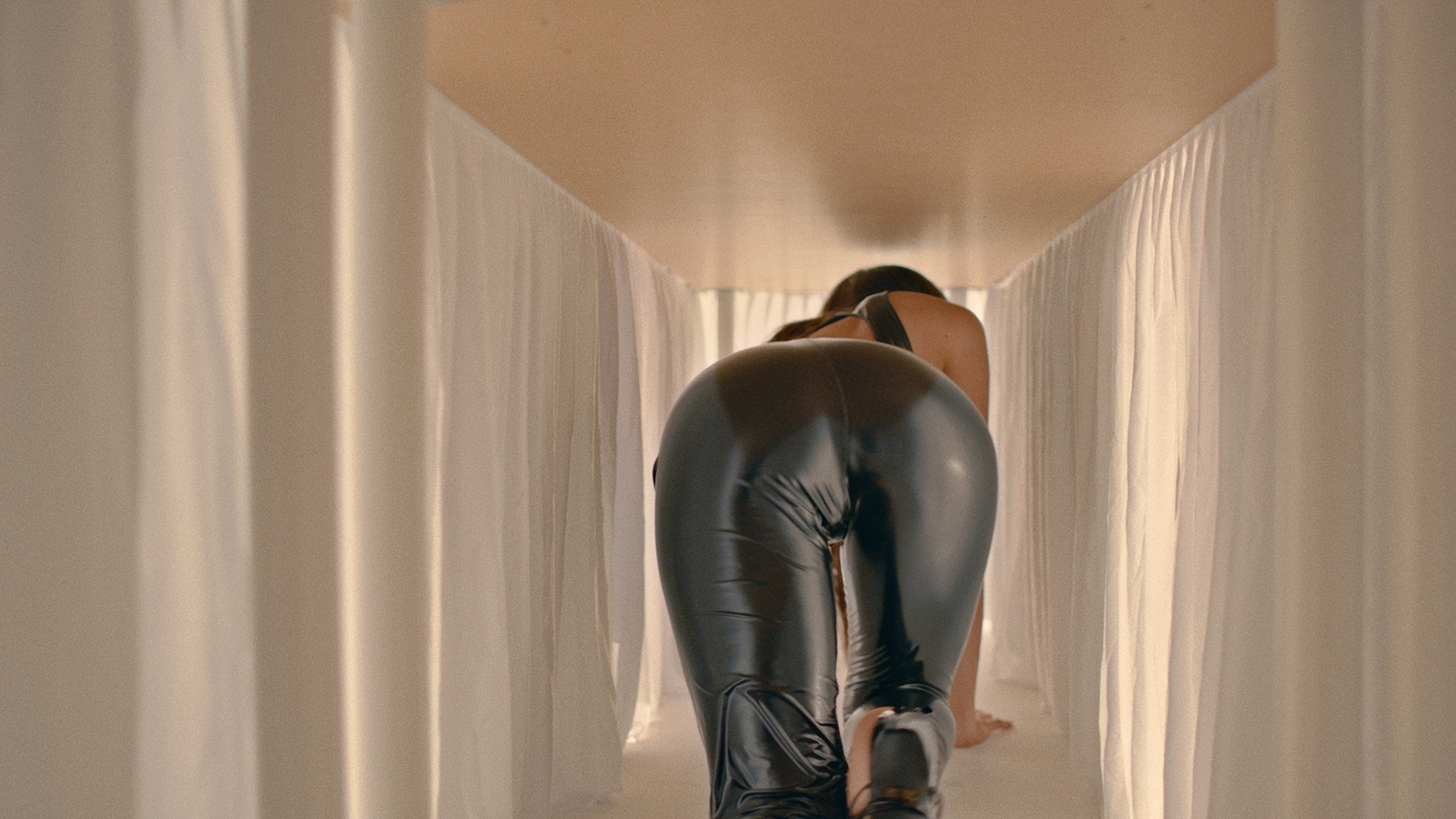 a woman in a black leather outfit walking down a hallway