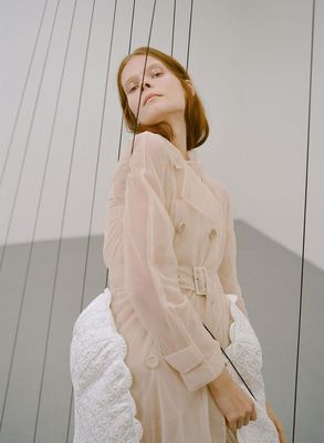 a woman in a beige dress holding a white purse