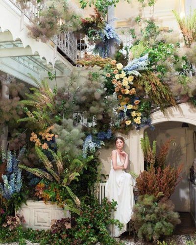 a woman sitting on a bench surrounded by plants