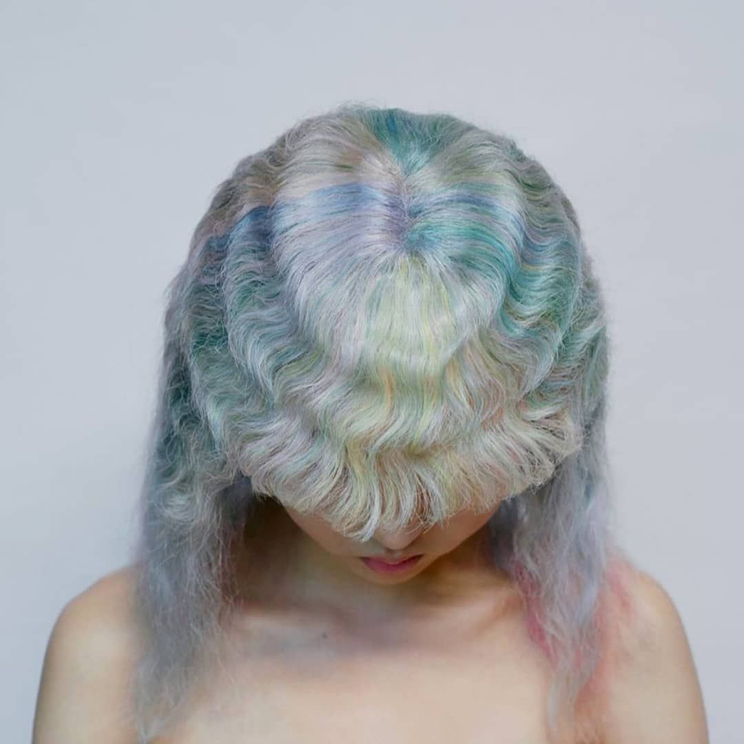 a woman with pastel hair is looking down