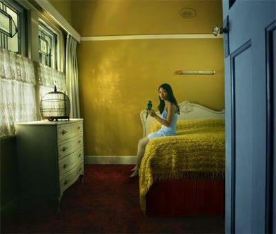 a woman sitting on top of a bed next to a dresser