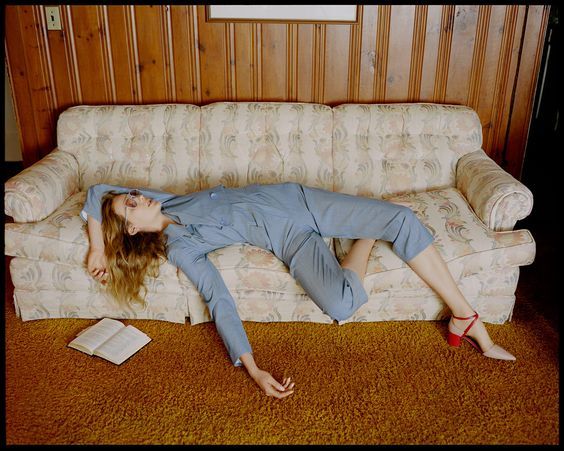 a woman laying on a couch next to a book