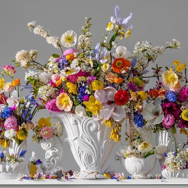 a group of white vases filled with colorful flowers