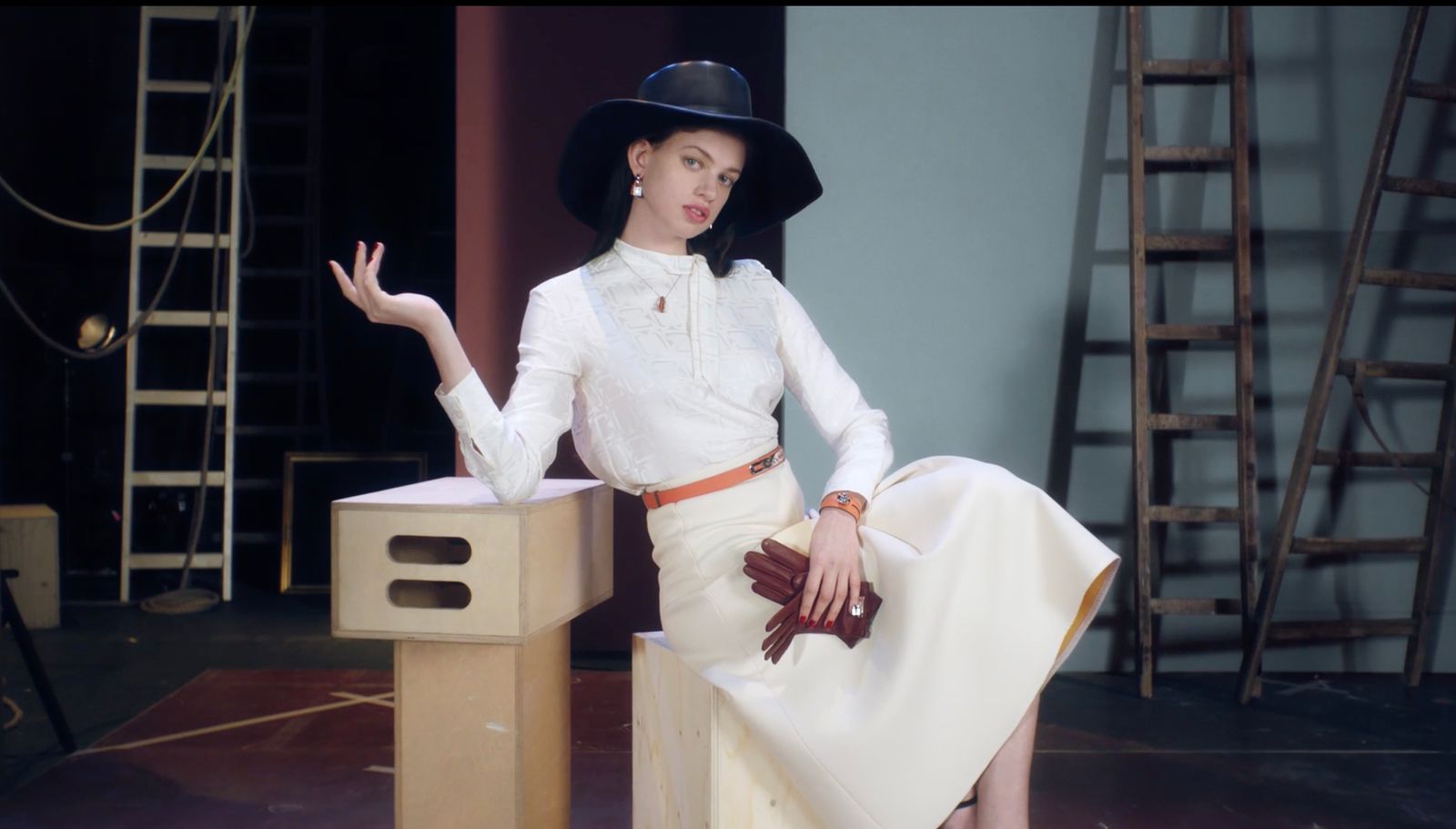 a woman in a white dress and hat sitting on a box