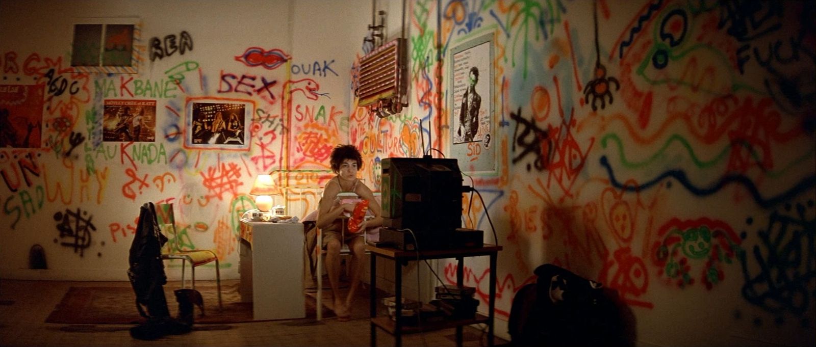 a person sitting in a room with a lot of graffiti on the wall