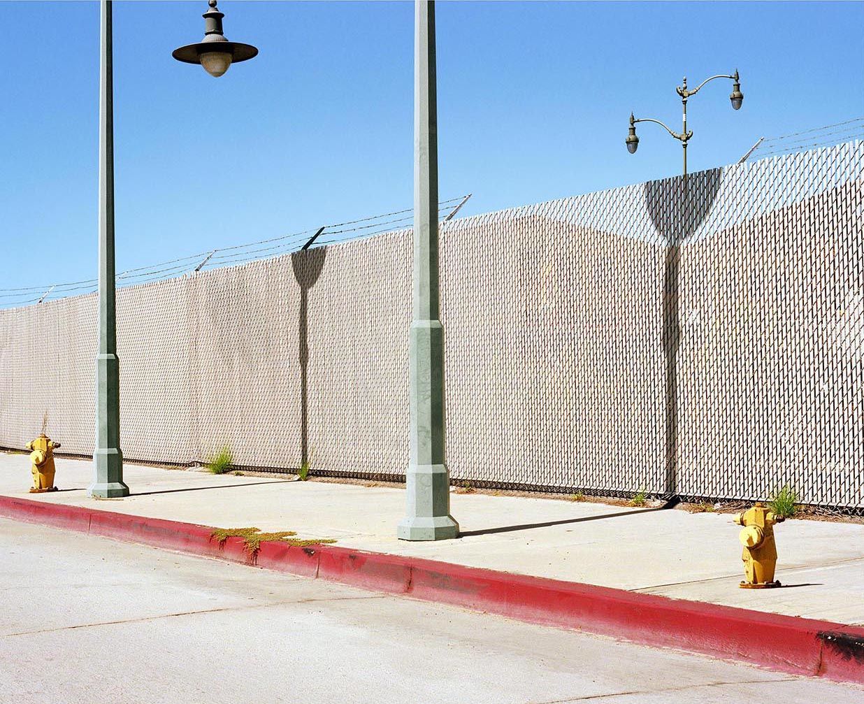 a row of fire hydrants sitting next to a fence