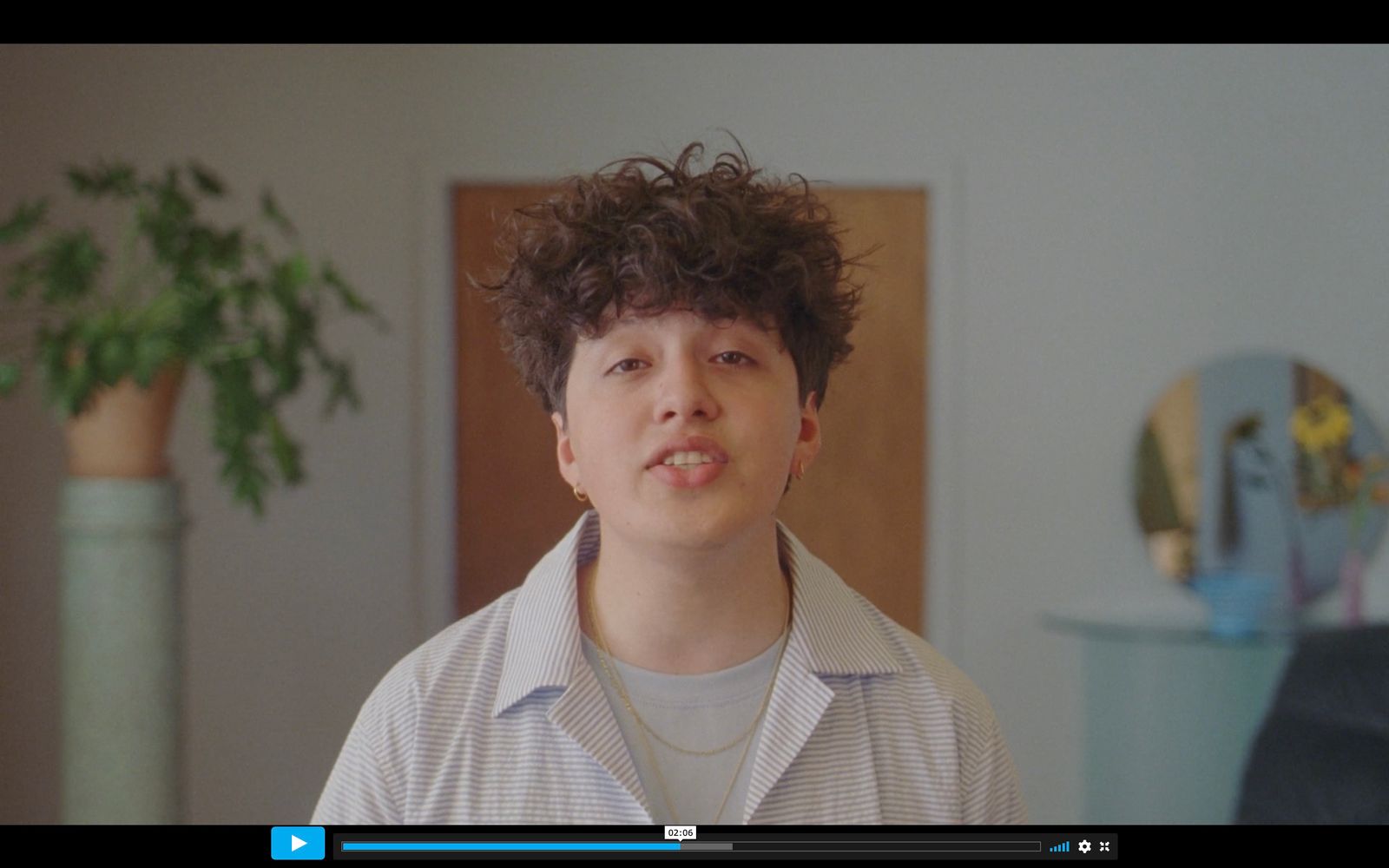 a man with curly hair standing in a room