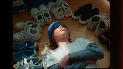 a young boy laying on the floor surrounded by shoes