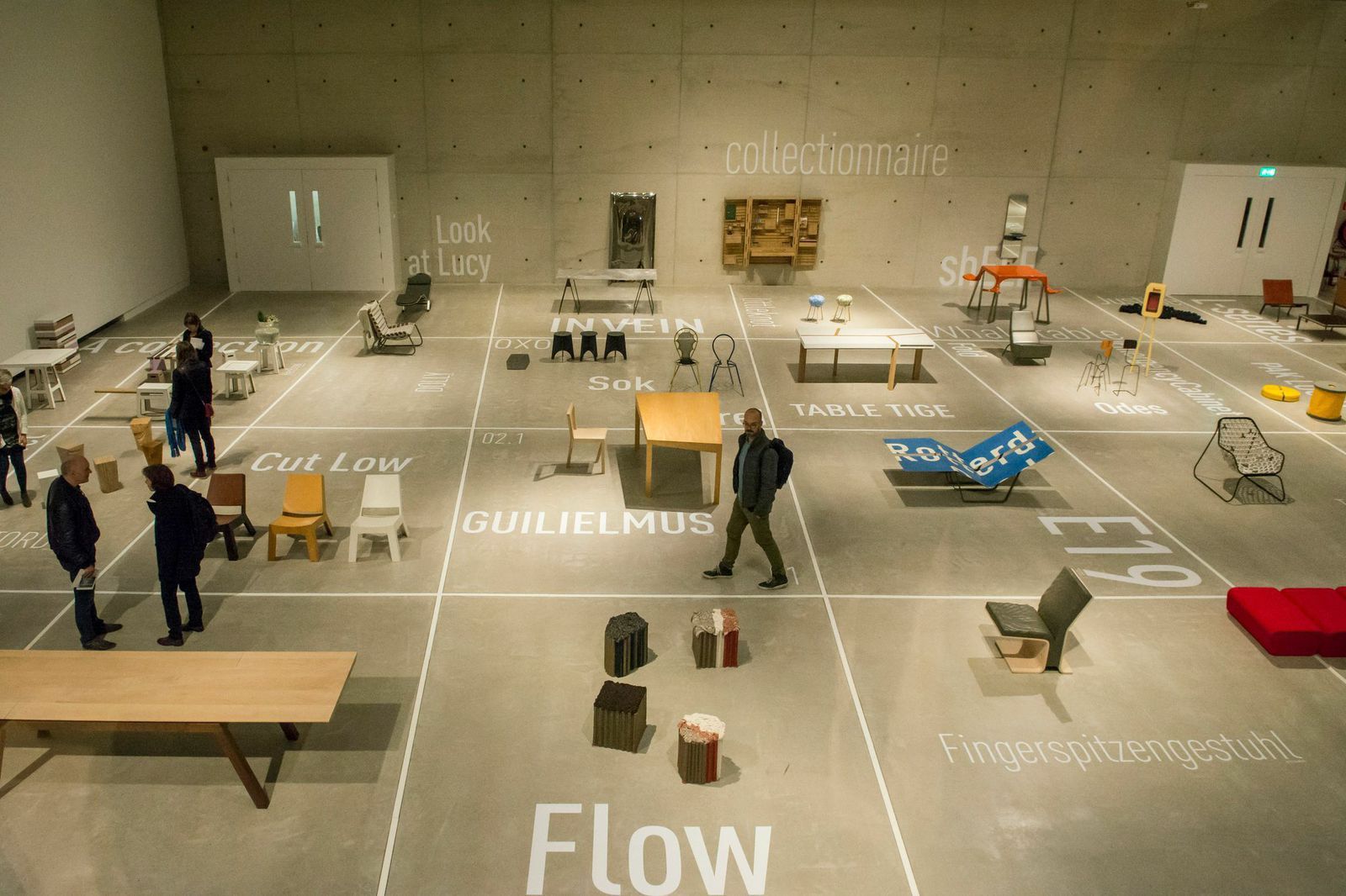 a group of people standing around a room filled with furniture