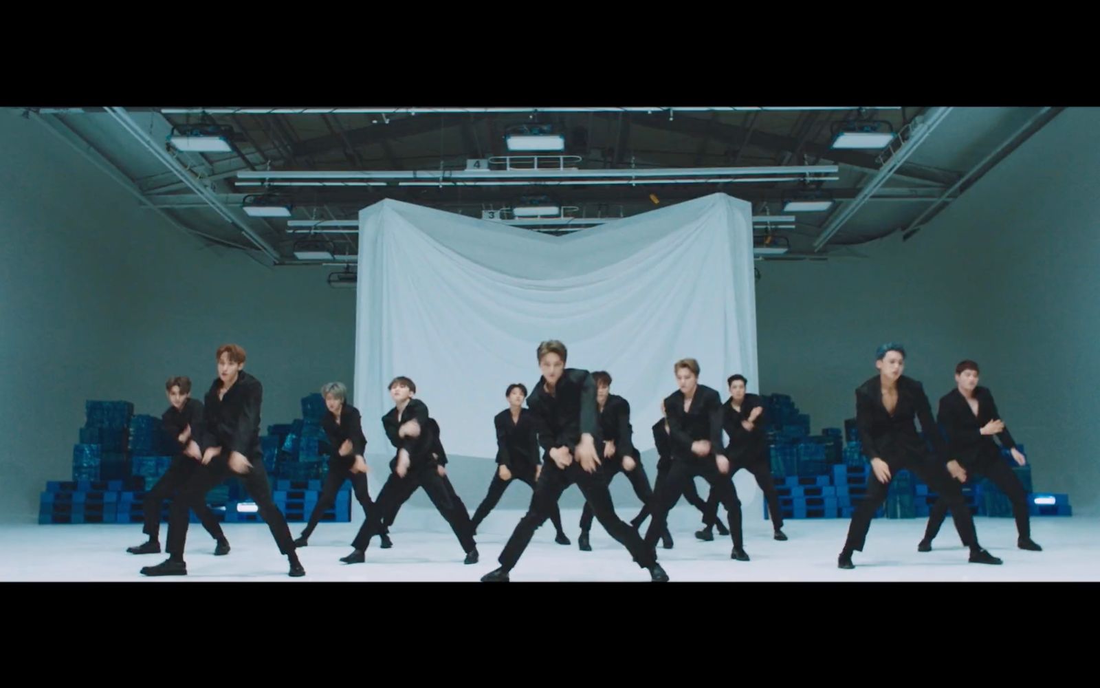 a group of young men dancing in front of a white curtain