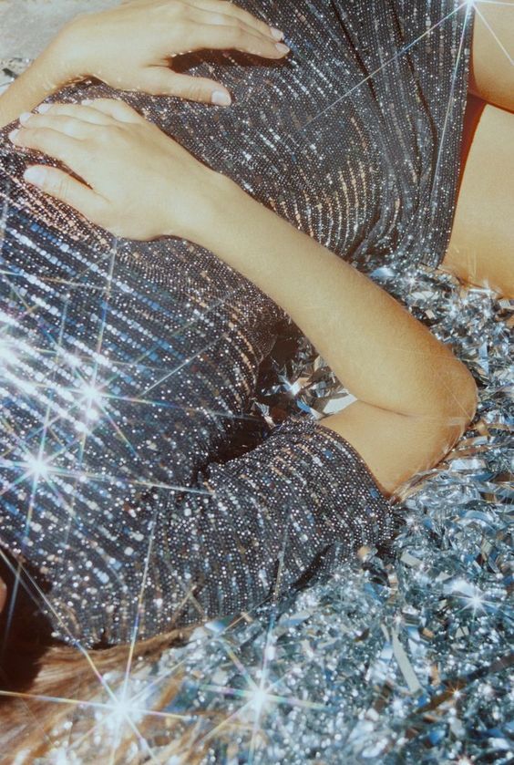 a woman laying on top of a bed covered in glitter