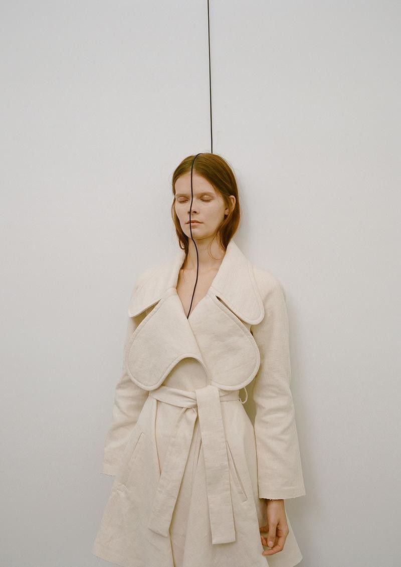 a woman standing in front of a white wall