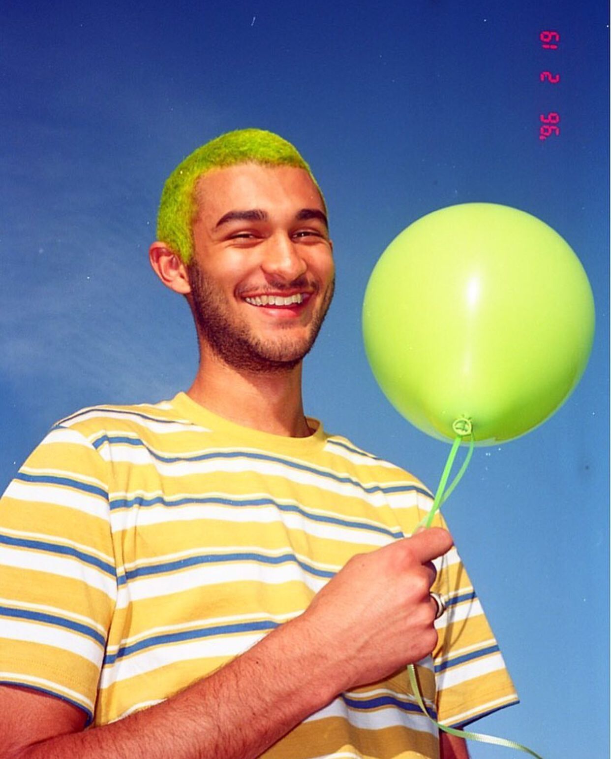 a man with green hair holding a green balloon