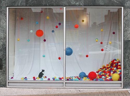 a cat sitting in a window with a bunch of balls in front of it