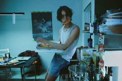 a man holding a pizza in a kitchen