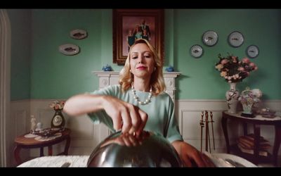 a woman sitting on a bed holding a tea kettle