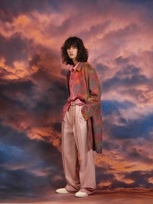 a woman standing in front of a cloudy sky