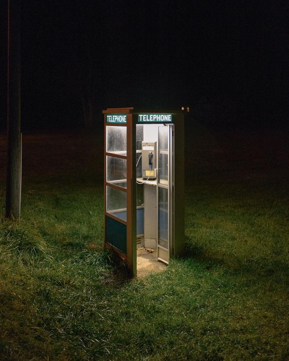 a phone booth sitting in the middle of a field