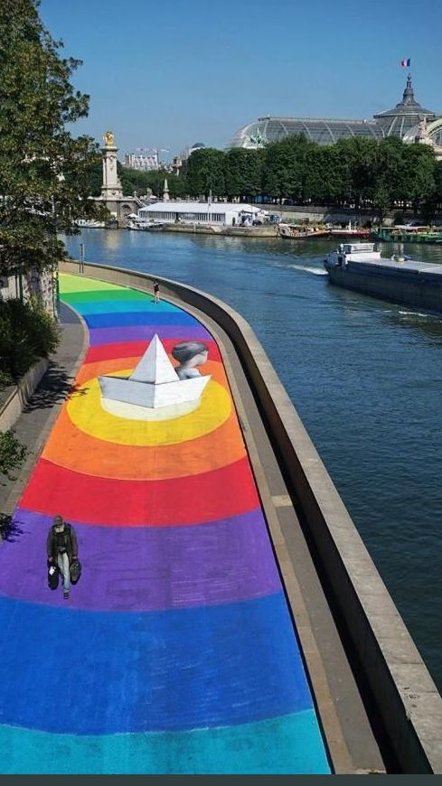 a rainbow painted walkway next to a river