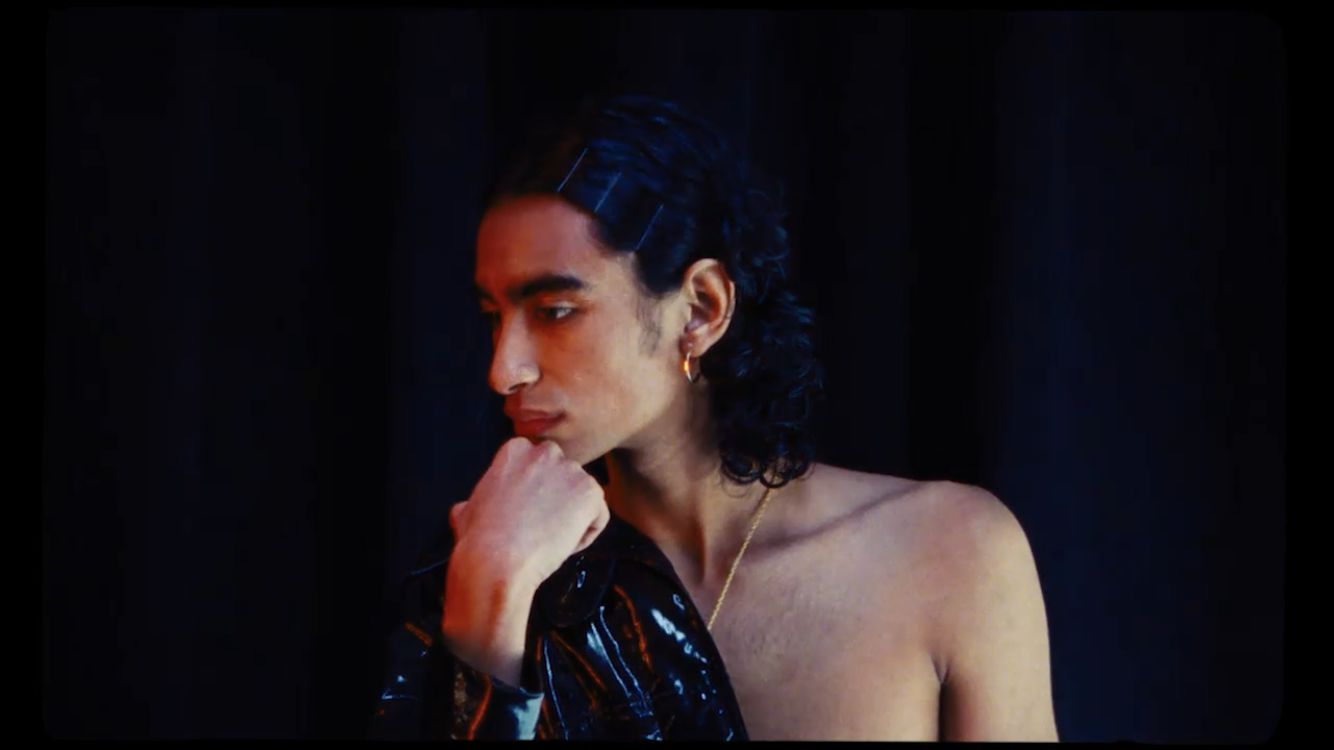 a shirtless man in a shiny black dress