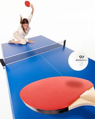 a woman is playing ping pong on a ping pong table